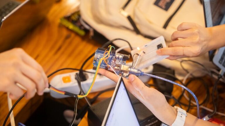 A detailed view of a team collaborating on an Arduino project featuring wiring and a breadboard.