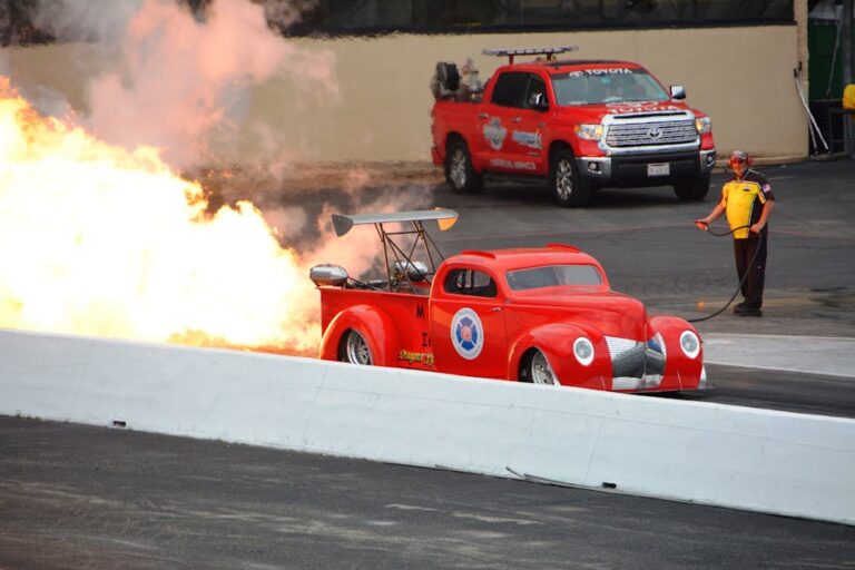 A powerful dragster car produces explosive flames during a thrilling race at a speedway.