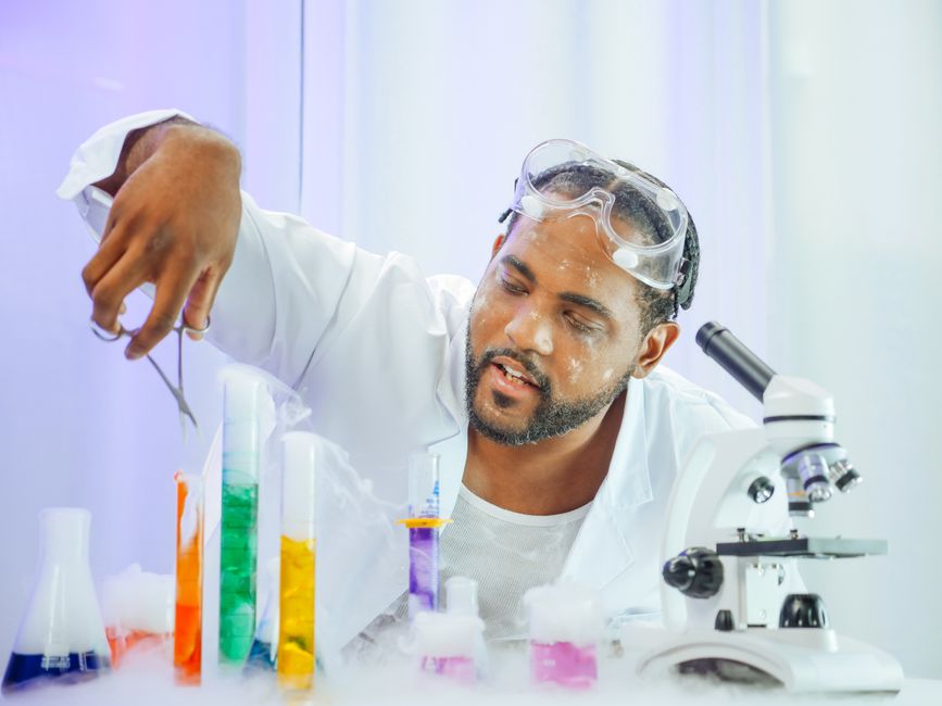 A scientist in a lab coat working with colorful liquids in a laboratory setting.
