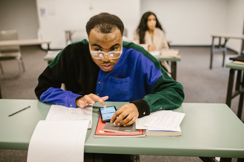 A student discreetly uses a smartphone during an exam, symbolizing modern classroom challenges.