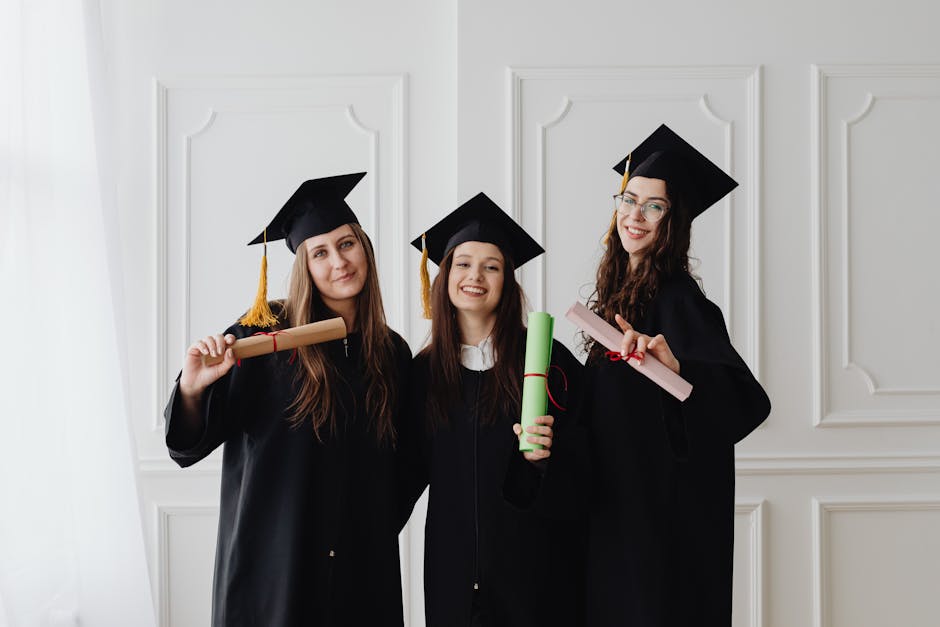 Three women in graduation gowns celebrating their academic achievements with diplomas.