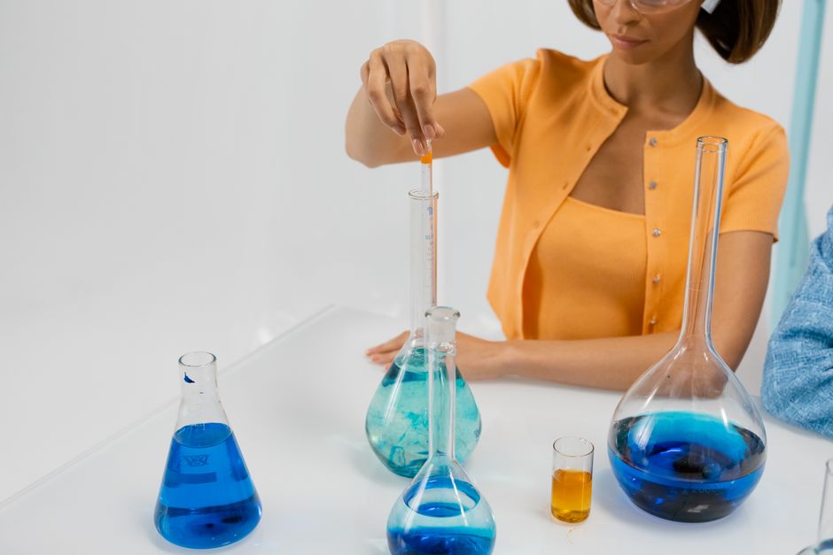 Woman conducting experiment in lab with various flasks and blue liquids.
